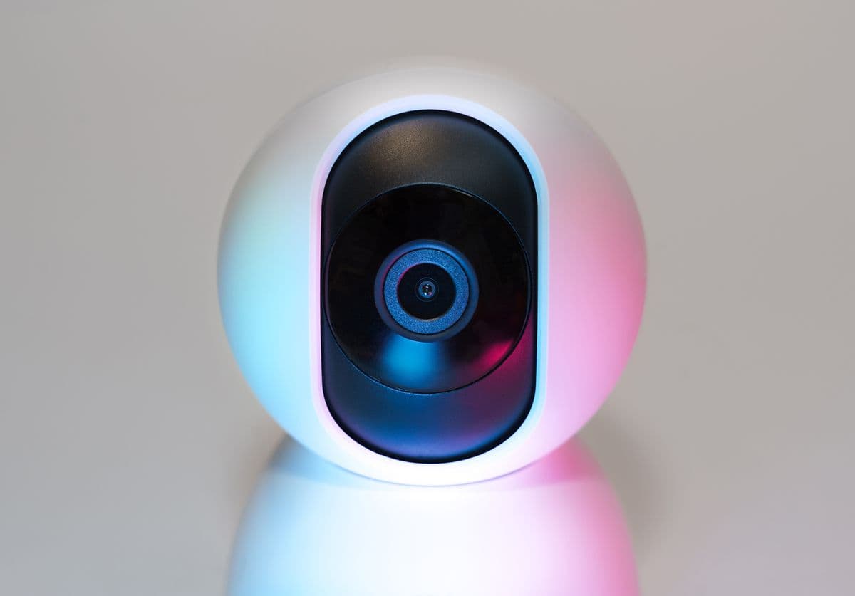 A modern smart camera lit with blue and pink accent lighting
