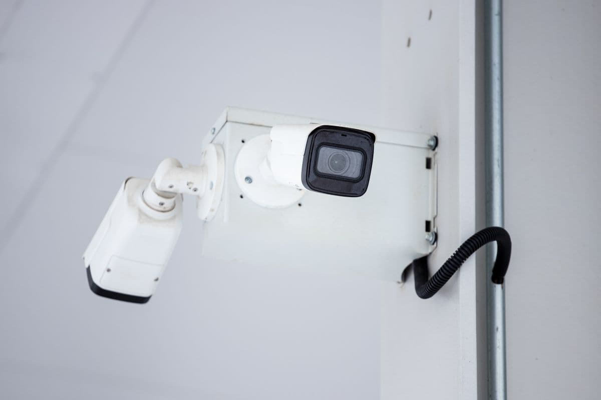 A white network IP camera mounted on a wall with its cable visible